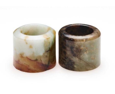 □ TWO CHINESE JADE ARCHERS RINGS, QING DYNASTY, 19TH CENTURY comprising: a celadon and russet jade ring, 2.7cm high; and a ce