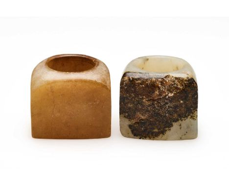 □ TWO CHINESE JADE ARCHERS RINGS, QING DYNASTY, 19TH CENTURY comprising: a caramel jade ring with flattened side, 2.2cm high;
