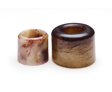 □ TWO CHINESE JADE ARCHERS RINGS, QING DYNASTY, 19TH CENTURY comprising: a large celadon and brown jade ring, 2.8cm high; and