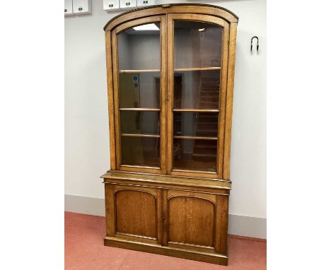 A XIX Century Oak Bookcase, with arched pediment over twin glazed doors, the base with arched panelled doors, on a plinth bas