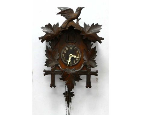A Mid XX Century Cuckoo Clock, in the Black Forest style carved with leaves with bird surmount, pendulum and two acorn weight