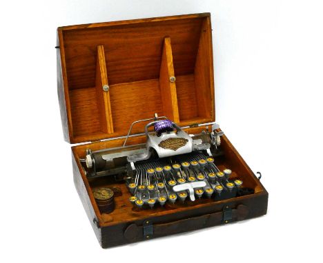 A Blickensderfer Feather Weight Aluminium Typewriter, with accessories in a wooden travelling case.