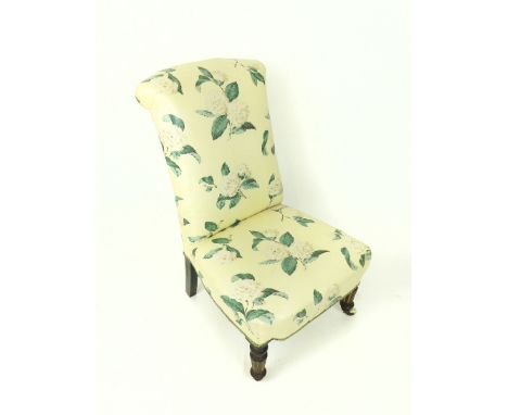 A 19th century, petite, nurse's chair, covered in a charming, cream-coloured floral chintz fabric on turned ebonised feet (th