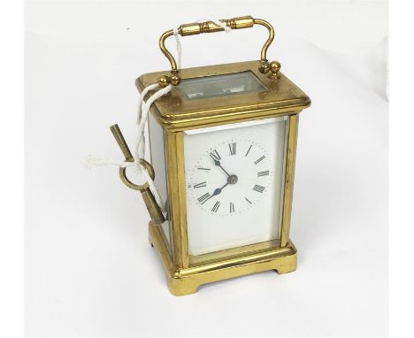 A brass carriage clock with Roman numeral dial, with key.