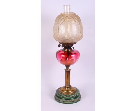 A brass, ruby glass and ceramic table oil lamp with chimney and frosted shade, 25" high