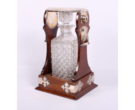 A late Victorian oak and silver mounted single bottle tantalus, fitted two side handles, with a square hobnail cut decanter a