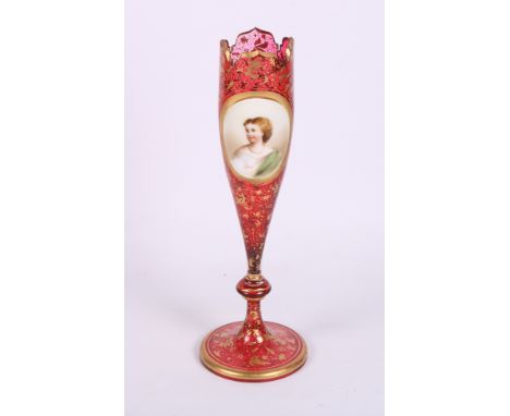 A late 19th Century bohemian ruby glass spill vase with scrolled foliate gilt decoration and enamel panel decorated with the 