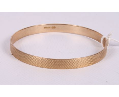 A 9ct gold bangle with engine turned decoration, 30.2g