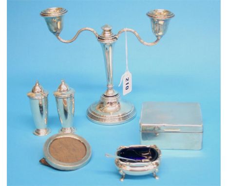 An engine turned silver cigarette box, a miniature silver photograph frame, a small silver candelabra and a silver three piec