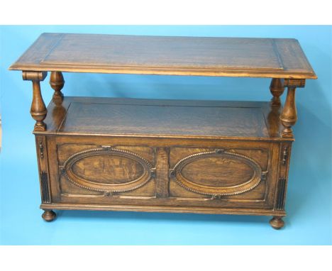 An oak monk's bench with circular panelled and beadwork back, rising seat and oval panels to the front.  112 cm long
