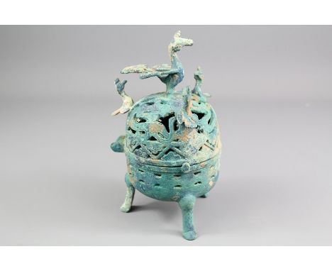 An Islamic Bronze Incense Burner. The burner on three legs with pierced decoration and depicting a peacock finial, approx 20 