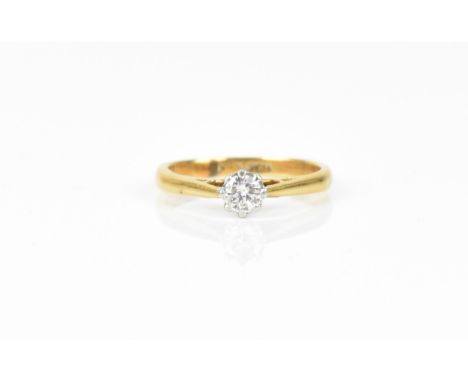 An 18ct yellow gold, platinum and diamond solitaire ring, the brilliant cut stone set in an eight claw setting, size M 