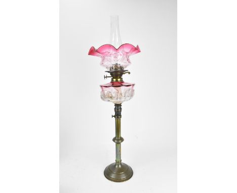 A Victorian cranberry and clear glass oil lamp, with moulded glass font , the shade with frill rim , on a brass stem with cir