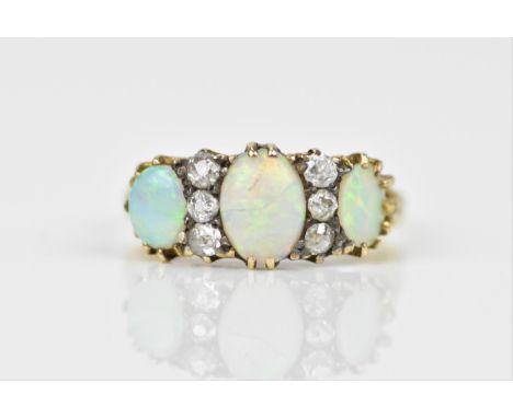 A yellow metal, opal and diamond dress ring, set with a central oval cabochon opal between three old mine cut diamonds either