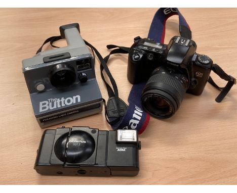 A Canon EOS 500 SLR camera with 35-80mm lens, a Polaroid "The Button" land camera and another (3)