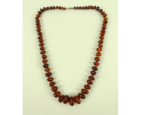 A vintage amber bead necklace, of clear treacle colour with some inclusions, 63cm long, beads graduating from 0.7 to 1.8cm, 3