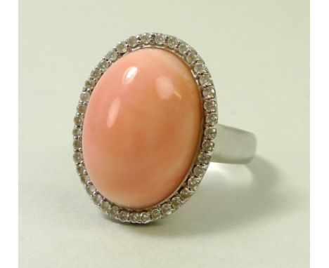 A coral and diamond ring, the oval angel pink cabochon within a surround of brilliant cut diamonds, stamped with a Hong Kong 