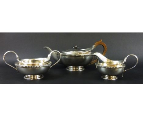 A George V silver three piece tea set, comprising teapot, sugar bowl and milk jug, the teapot of simple squat circular form, 