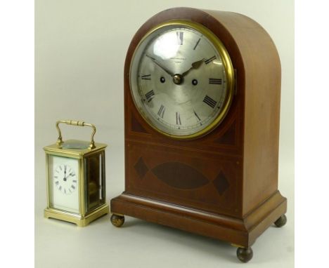 An early 20th century mahogany cased mantel clock, of domed form with inlaid panels and line decoration, silvered dial signed