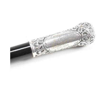 A George V cased hallmarked silver and ebony conductors baton. The baton having a silver pommel and collar decorated with an 