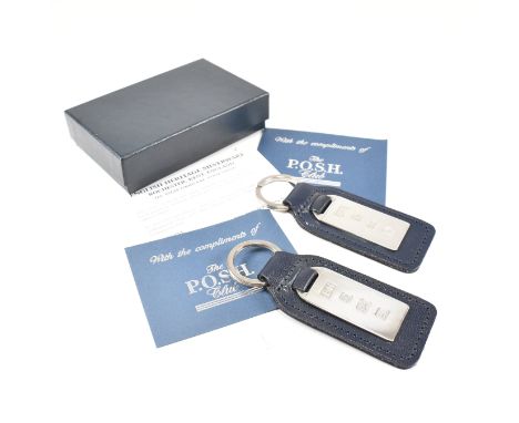 Two 1990s hallmarked silver and leather tag keyrings. The silver tags backed with navy blue leather stamped to the back 'The 