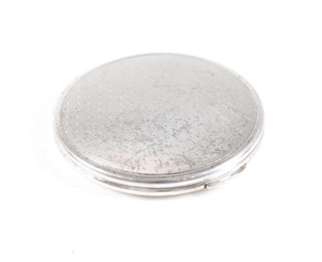 A Mid century hallmarked silver compact. The compact being of circular form with hinged opening and having an engine turned d