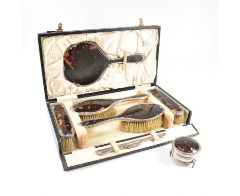 A George V hallmarked silver and tortoiseshell mounted, cased vanity set. The six piece set to include two hair brushes, two 
