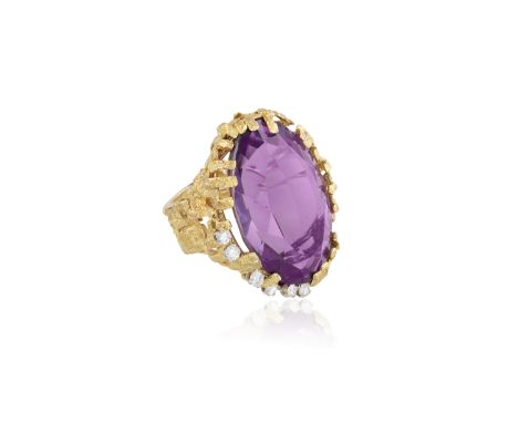 AN AMETHYST AND DIAMOND COCKTAIL RING, CIRCA 1970The large oval-shaped amethyst, set within an openwork textured gold mount w