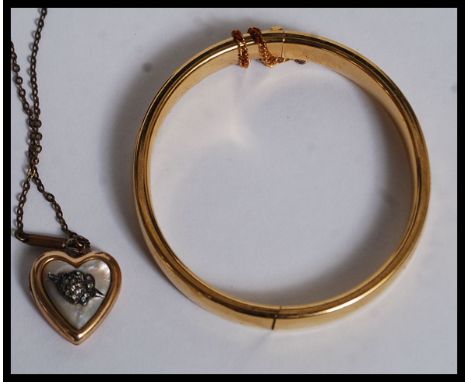 A good quality rolled gold bangle / bracelet with safety chain together with a  gold plated and mother of pearl faced pendant