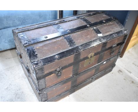 A traditional dome topped travel trunk with wooden bindings, metal edges and canvas leather work