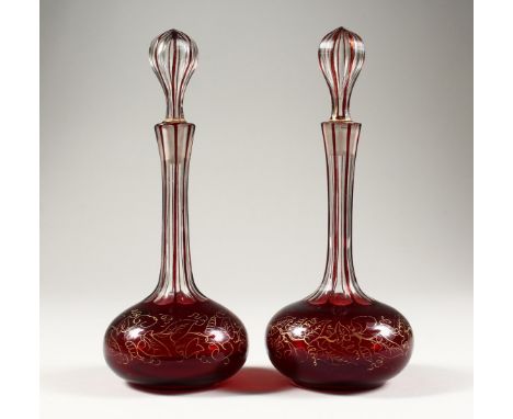 A PAIR OF RUBY OVERLAID AND GILT DECORATED CUT GLASS PERFUME BOTTLES 8.5ins high