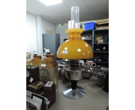 A large oil lamp having mustard yellow glass shade and transparent inner chimney.