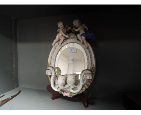 An antique hard paste mirror with Cherub decal and integral candle sticks marked R to top