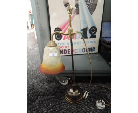 An adjustable brass bodied reading lamp with smoked red glass shade 