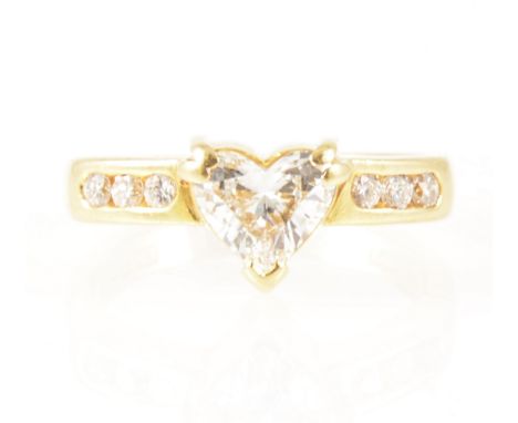 A heart shaped diamond ring with diamond shoulders, the heart shaped diamond set by three corner claws in an all yellow gold 