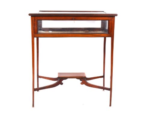 An Edwardian glass-top display table, crossbanded and boxstrung outlines, square tapering supports joined by cross stretchers