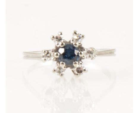 A sapphire and diamond circular cluster ring, a 4.2mm sapphire claw set and surrounded by six 8 cut diamonds in an all white 