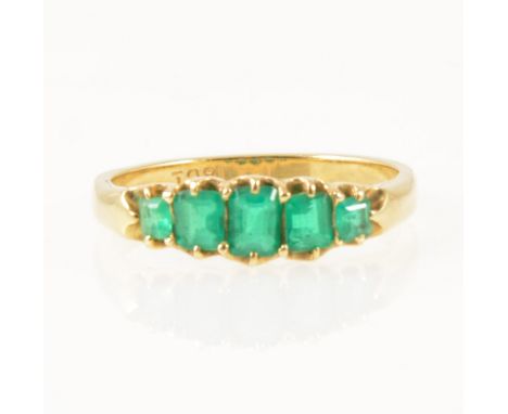 An emerald five stone half hoop ring, the graduated step cut stones claw set in an all yellow gold mount marked 18ct on shank