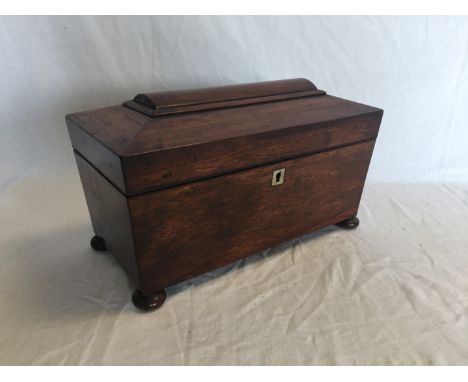 A Victorian mahogany sarcophagus form tea caddy with central circular recess flanked by two apertures raised on squat bun fee