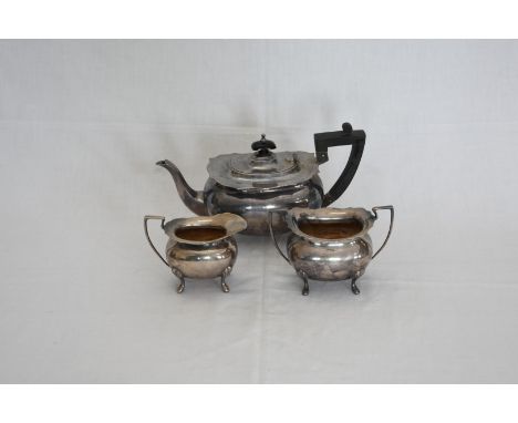 A plated three piece tea set comprising teapot with angular ebony handle and finial, milk jug and twin handled sugar bowl.  