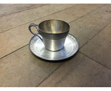 A French silver plated cup and saucer, the cup with leaf and berry decorated handle, the body with engine turned decoration a