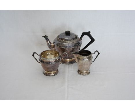 A plated three piece tea set with Celtic style decoration to the body, comprising teapot with angular ebony handle, milk jug 