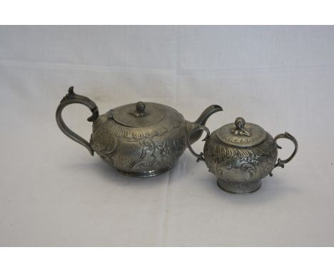 A pewter twin handled sugar bowl and cover with embossed flower head, scroll and leaf decoration with touch mark to base and 