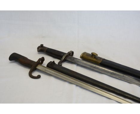 An 18” bayonet with brass and black leather scabbard and a 20½ins French bayonet, the top of the 14” blade engraved 1879. 