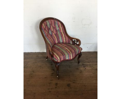 A Victorian mahogany button back armchair with striped material, scrolled pierced arm terminals, over-stuffed serpentine fron