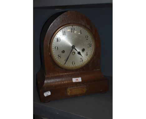A 1920s oak chiming mantel clock, having plaque to foot reading 'Presented to Mr W H Green, by his colleagues of the A/Cs dep