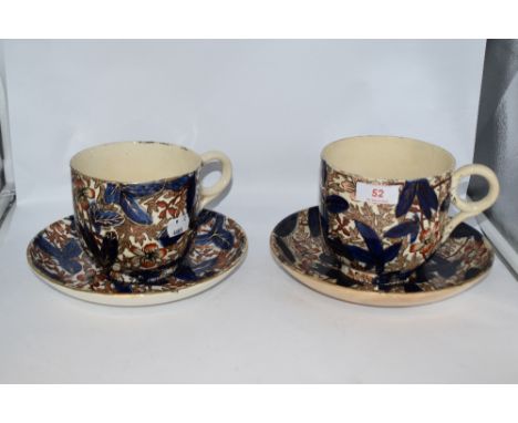Two 19th century oversized cups and saucers, having floral pattern in blue and rust tones, heightened with gilt on natural gr