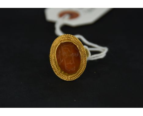 A cornelian intaglio, possibly Pan, to a gold ring mount with cord decoration to the head and shank, possibly Roman finger si