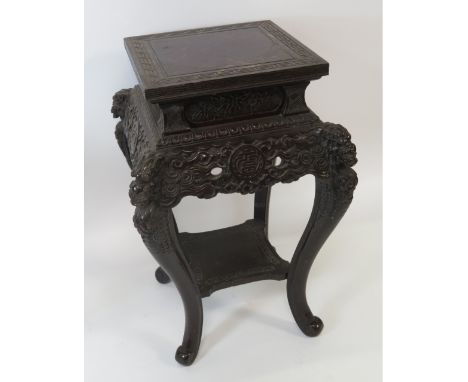 A Chinese hardwood stand of square form, the cabriole supports carved with Kylin masks, clouds and joined by lower shelf, 78c