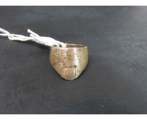 A metal archers thumb ring, engraved with lettering and a satyr firing a bow and arrow